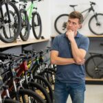 Osoba zastanawiająca się jaki rower kupić, przeglądająca różne modele w sklepie rowerowym