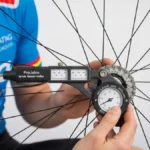 Rowerzysta używający tensjometru do pomiaru napięcia szprych na kole rowerowym